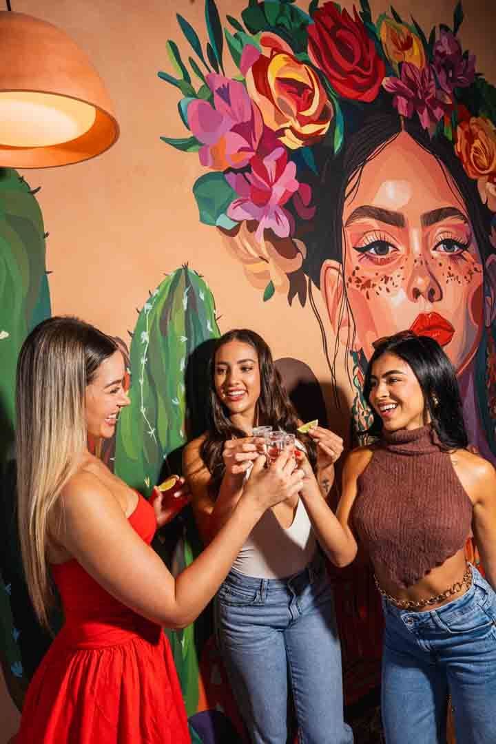 Guests toasting in front of the hand-painted cactus and flower-crown mural