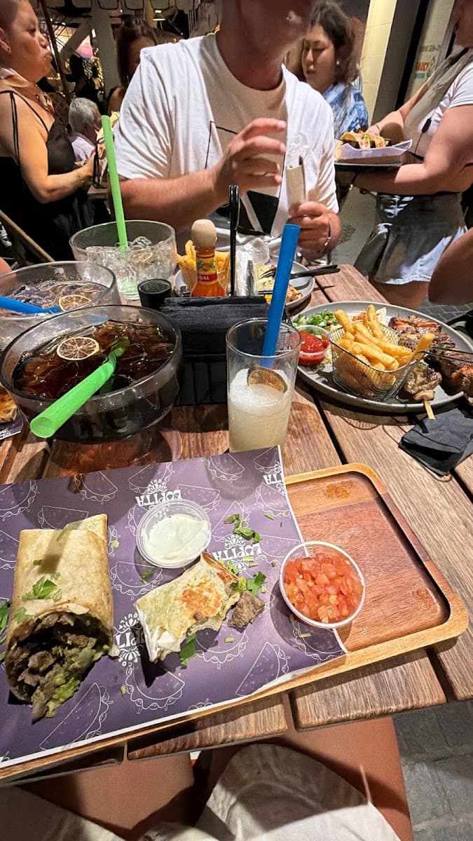 A table full of tacos, burritos and drinks shared among friends